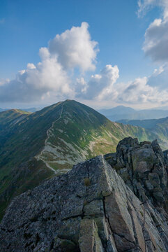 View of jagged rocks meet the sky, leading to a verdant peak under a sky dotted with fluffy clouds, a scenic vista of nature's raw beauty, Zuberec, Zilinsky kraj, Slovakia.