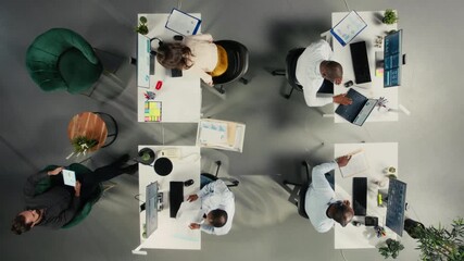 Top down view of workers in multinational company discuss business strategy and performance metrics. Staff consult on forecasting, report sharing and data while aligning objectives. Camera A. - Powered by Adobe