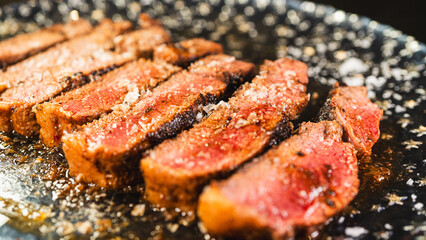 Sliced rare rump steak on a plate, revealing pink interior under a beautiful golden crust. Topped with salt, juicy and perfectly cooked. Gourmet meat presentation.