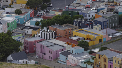 View of vibrant, multicolored buildings nestled together creating a patchwork of colors, with cars parked between the buildings, Cape Town, Western Cape, South Africa.