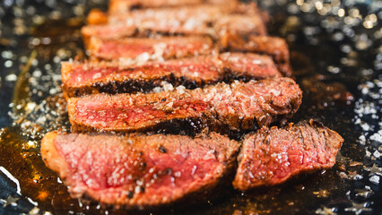 Sliced rare rump steak on a plate, revealing pink interior under a beautiful golden crust. Topped with salt, juicy and perfectly cooked. Gourmet meat presentation.