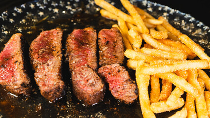 Sliced rare rump steak served with golden French fries on a plate. Pink interior, beautiful crust, topped with salt. Classic hearty meal, juicy and satisfying.