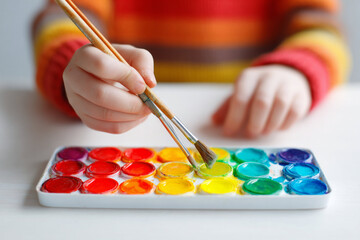 Creative child uses watercolor paints to make colorful artwork on a bright day