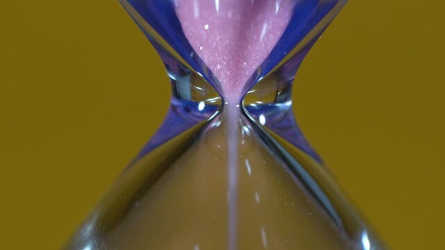 Hourglass, detail of the pink sand passing through the narrow, constricted tube.