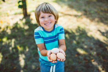 Little boy smiling holding fresh chicken eggs