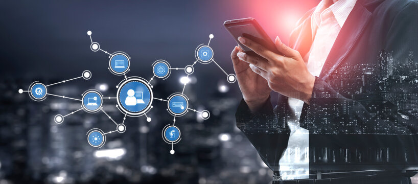 A businessman in a formal suit engages with a smartphone, surrounded by digital connection icons. The urban night background highlights modern technology and networking. Tessel