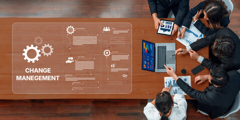 A business team engages in collaboration focused on change management within a modern office environment, utilizing various data presentation tools and strategies. Trope