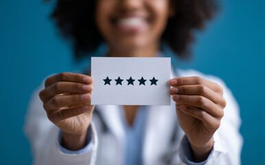 Smiling female doctor holds five star rating card, showcasing her commitment to quality care and patient satisfaction