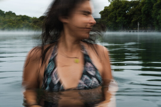 Woman shaking head in lake water with blurred motion effect