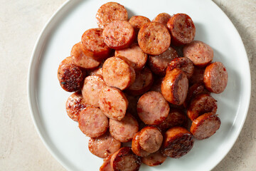 A top down view of a pile of sliced andouille sausage, on a plate.