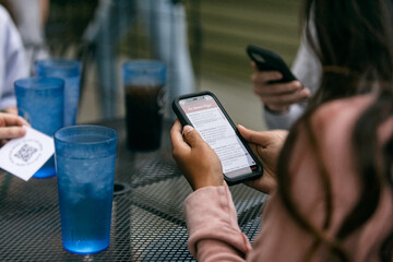 Dining: Woman Uses Phone To Look At Restaurant Menu
