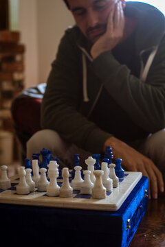 Focused Player Engages in Chess Match at Home