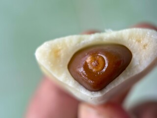 Macro close-up of the fleshy white segments and dark brown seed of a peeled Salak (Salacca zalacca)/Snake Fruit, highlighting the raw tropical food texture.