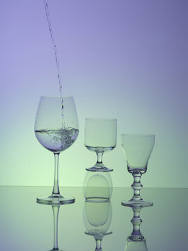 Water cascading into a wine glass, next to two other glasses