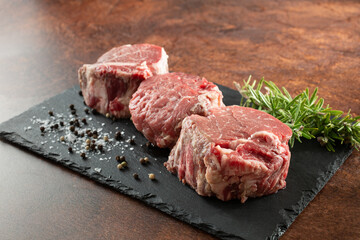 A view of some raw filet mignon on a slate board.