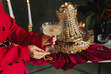 Hands holding sparkling champagne glass over a festive Christmas table with new year decoration.