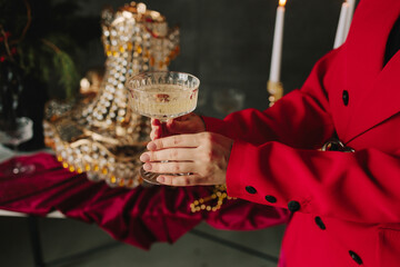 Hands raising champagne glass over holiday table with decorations.