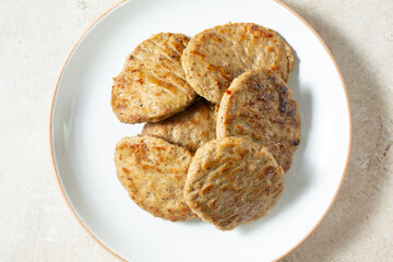 A top down view of a pile of chicken sausage patties, on a plate.