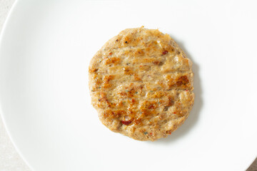 A top down view of a single chicken sausage patty, on a plate.