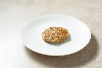 A view of a single chicken sausage patty, on a plate.