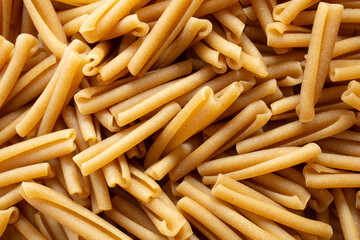 A top down view of a pile of dry gluten-free casarecce pasta, as a background.