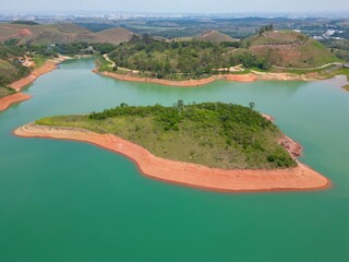 Vista do alto a seca da represa cercada de vegeta&ccedil;&atilde;o e natureza com cores vibrantes.
