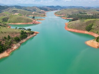 Vista do alto a seca da represa cercada de vegeta&ccedil;&atilde;o e natureza com cores vibrantes.