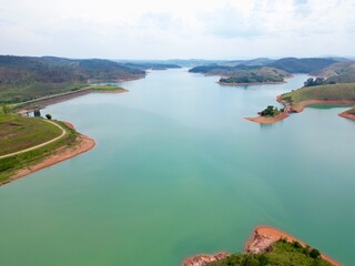 Vista do alto a seca da represa cercada de vegeta&ccedil;&atilde;o e natureza com cores vibrantes.