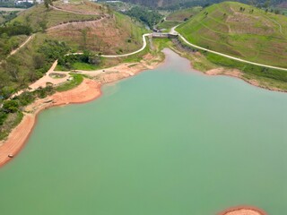 Vista do alto a seca da represa cercada de vegeta&ccedil;&atilde;o e natureza com cores vibrantes.