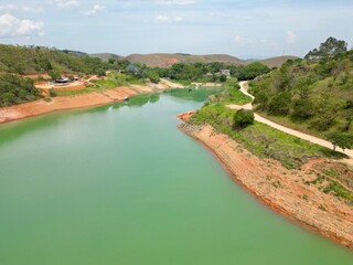 Vista do alto a seca da represa cercada de vegeta&ccedil;&atilde;o e natureza com cores vibrantes.