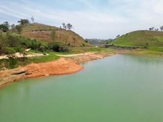 Vista do alto a seca da represa cercada de vegeta&ccedil;&atilde;o e natureza com cores vibrantes.