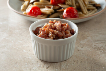 A view of a ceramic condiment cup of sauteed pancetta.
