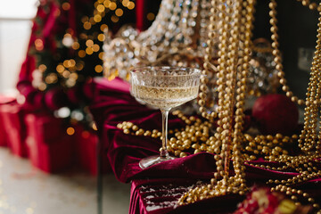 Sparkling champagne glass on Christmas table with crystal ornaments, candles, new year decorations.