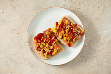 A top down view of a hot dog tartine, on a plate.