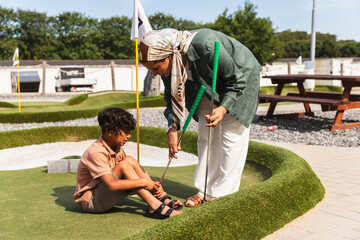 Caring Mother Comforting Her Sad Child on a Minigolf Course