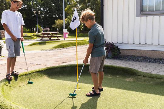 Siblings Playing a Friendly Game of Minigolf in the Summer