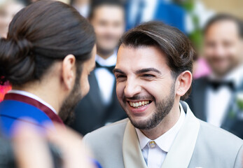 One groom smiles happily at the other during wedding ceremony