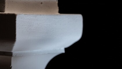 Closeup of white textured architectural molding against a black background
