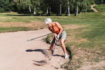 Senior woman Hitting a Golf Ball from a Sand Trap