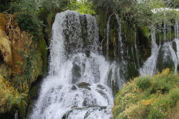 A dramatic natural waterfall crashing over moss-covered rocks, highlighting the raw power and beauty of untouched nature.