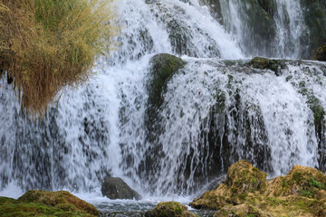 Editorial image of the Kravice Waterfall in Herzegovina, captured on August 24, 2025, showcasing cascading water over moss-covered rocks.