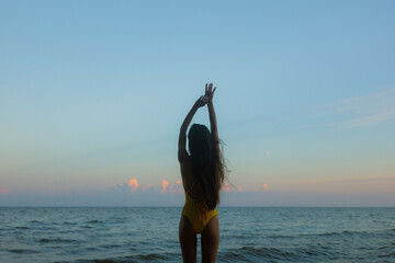 Woman Enjoying Sunset at the Beach With Arms Raised