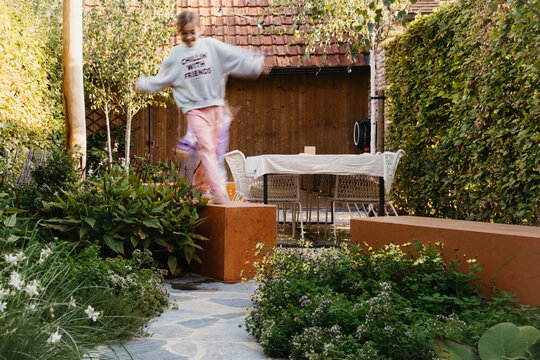 child joyfully jumping on a rustic garden pathway
