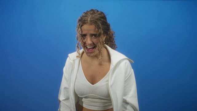 Woman with visible cleavage in white crop top and hoodie, mouth open shouting in studio; raw frustration.