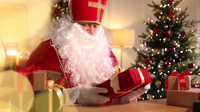 Saint Nicholas with gifts at desk in room decorated for Christmas. Camera moving forward - Powered by Adobe