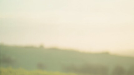 Fototapeta premium A soft, blurred landscape depicting rolling hills under a gentle sunrise, evoking a serene and tranquil atmosphere.
