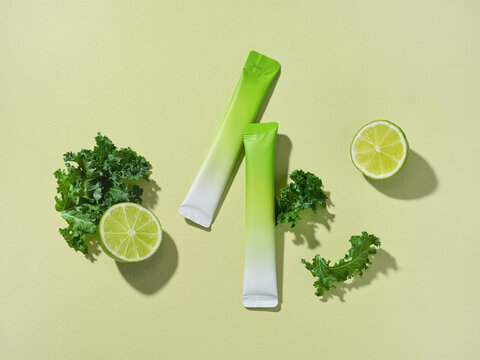 Vibrant flat lay featuring kale, lime slices, and a supplement