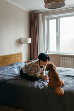 Woman Interacting With Dog in Cozy Bedroom Setting During Day