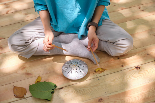 Chinese woman playing hollow drum in the woods, closeup