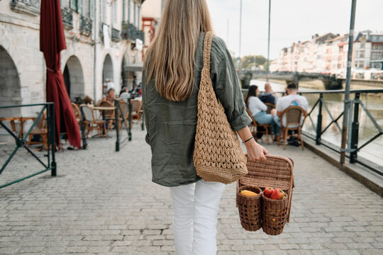 Woman Carrying Wicker Basket Full Of Fresh Greens And Fruits At Outdoo